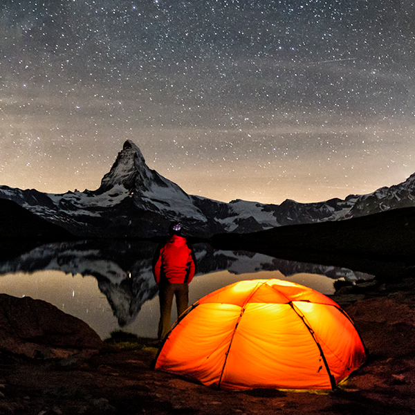 SAP Fiori App Engineering. Mann schaut in die Sterne neben einem orange leuchtenden Zelt stehend.